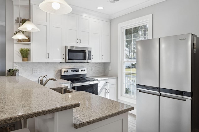 kitchen featuring hanging light fixtures, stainless steel appliances, plenty of natural light, and white cabinetry