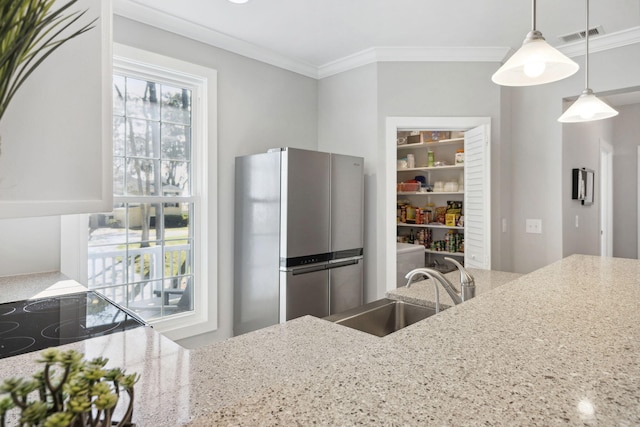 kitchen featuring stainless steel refrigerator, crown molding, decorative light fixtures, sink, and light stone counters