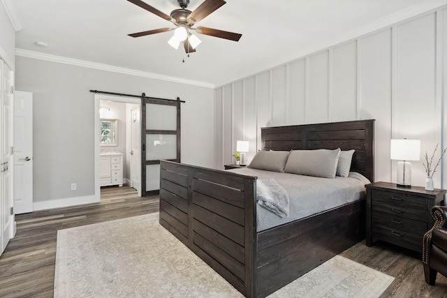 bedroom with ceiling fan, dark hardwood / wood-style floors, connected bathroom, crown molding, and a barn door