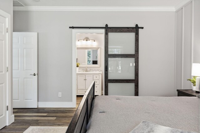 bedroom with dark hardwood / wood-style floors, sink, crown molding, ensuite bath, and a barn door