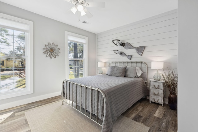 bedroom with ceiling fan, wood-type flooring, and multiple windows