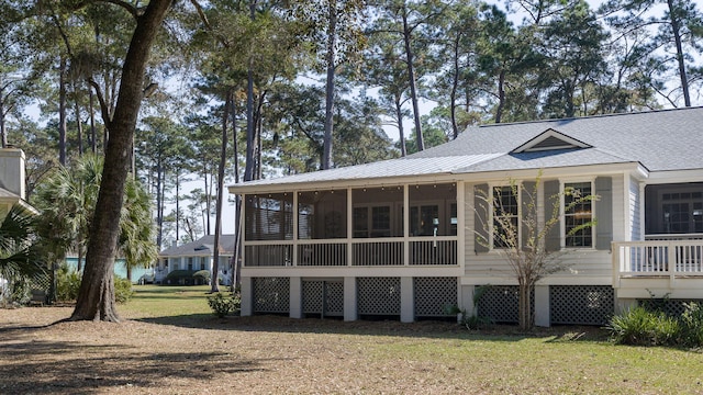 rear view of house featuring a sunroom and a lawn