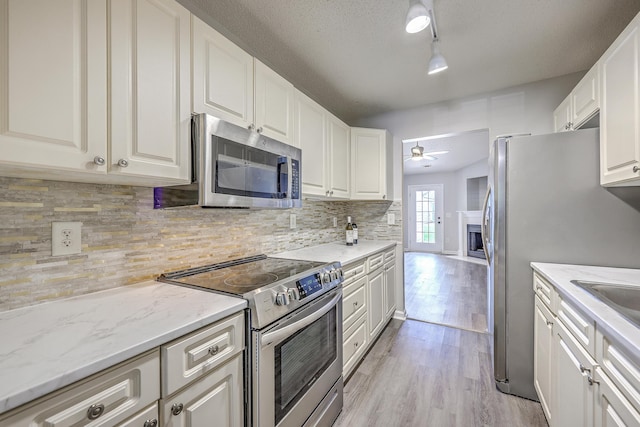 8028 Vermont Rd, North Charleston, SC 29418 - kitchen featuring stainless steel appliances, a fireplace, light wood-type flooring, ceiling fan, and backsplash