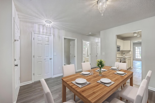 8028 Vermont Rd, North Charleston, SC 29418 - dining room with light wood finished floors, a chandelier, baseboards, and a textured ceiling