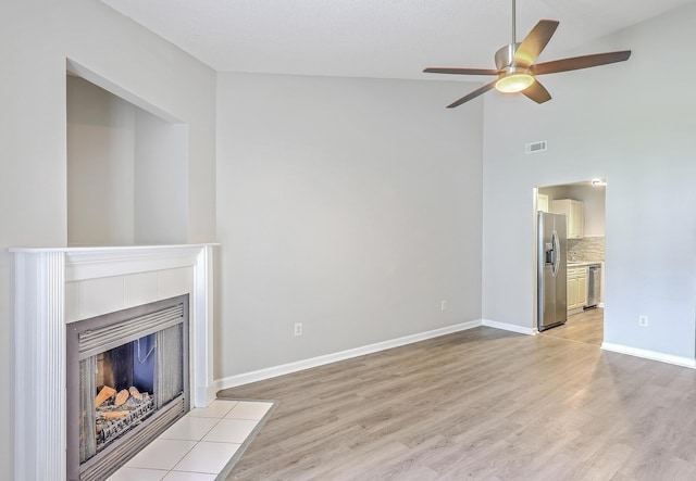 8028 Vermont Rd, North Charleston, SC 29418 - unfurnished living room with a ceiling fan, high vaulted ceiling, light wood-style flooring, a tile fireplace, and baseboards