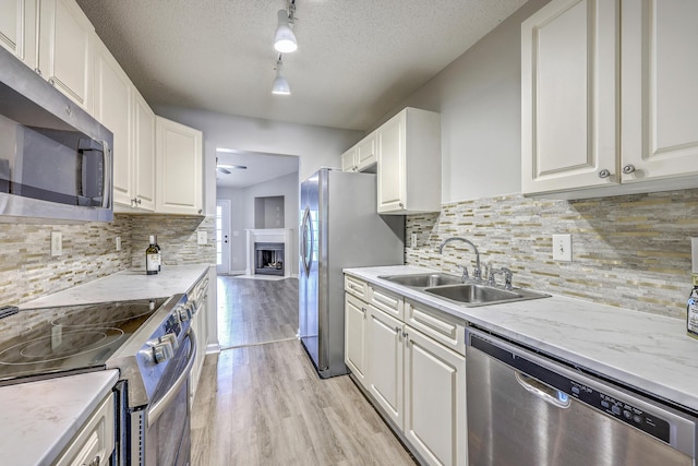 8028 Vermont Rd, North Charleston, SC 29418 - kitchen featuring stainless steel appliances, a sink, light wood finished floors, white cabinetry, and a fireplace