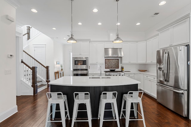 kitchen featuring a center island with sink, ventilation hood, hanging light fixtures, dark hardwood / wood-style floors, and stainless steel appliances