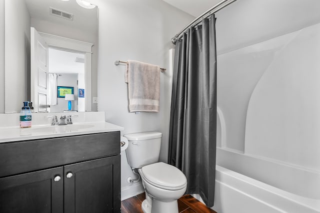 full bathroom featuring hardwood / wood-style floors, vanity, shower / tub combo, and toilet