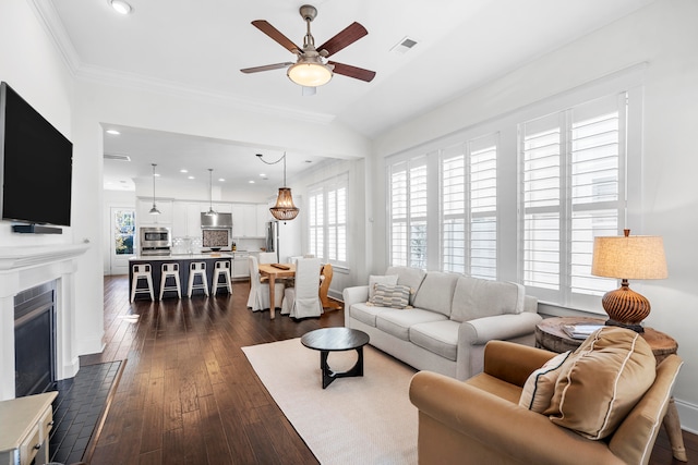 living room featuring dark hardwood / wood-style flooring, ceiling fan, and crown molding