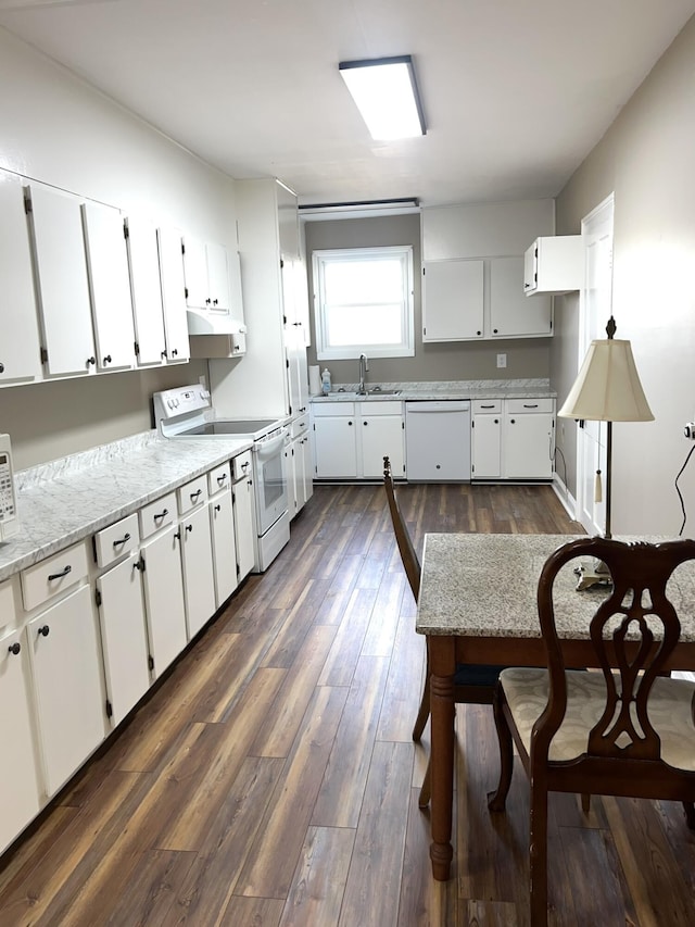 kitchen with sink, white appliances, white cabinetry, dark hardwood / wood-style floors, and light stone counters