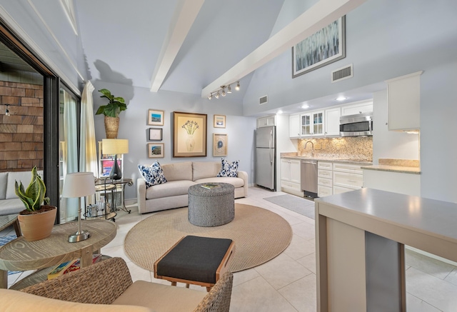 tiled living room with lofted ceiling with beams and rail lighting