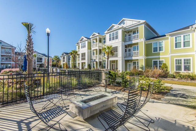 view of patio with an outdoor fire pit, fence, and a residential view