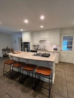 kitchen featuring white cabinetry, black gas stovetop, and a breakfast bar