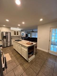 kitchen featuring white cabinetry, gas stovetop, a center island, and stainless steel refrigerator with ice dispenser