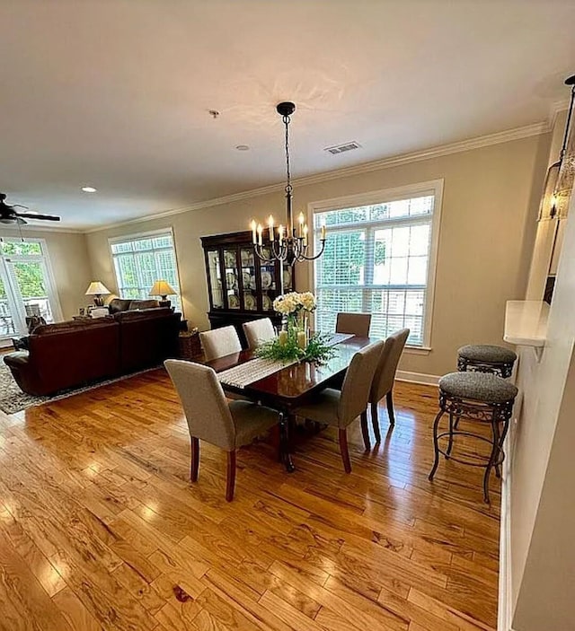 dining space featuring light hardwood / wood-style flooring, ceiling fan with notable chandelier, and ornamental molding