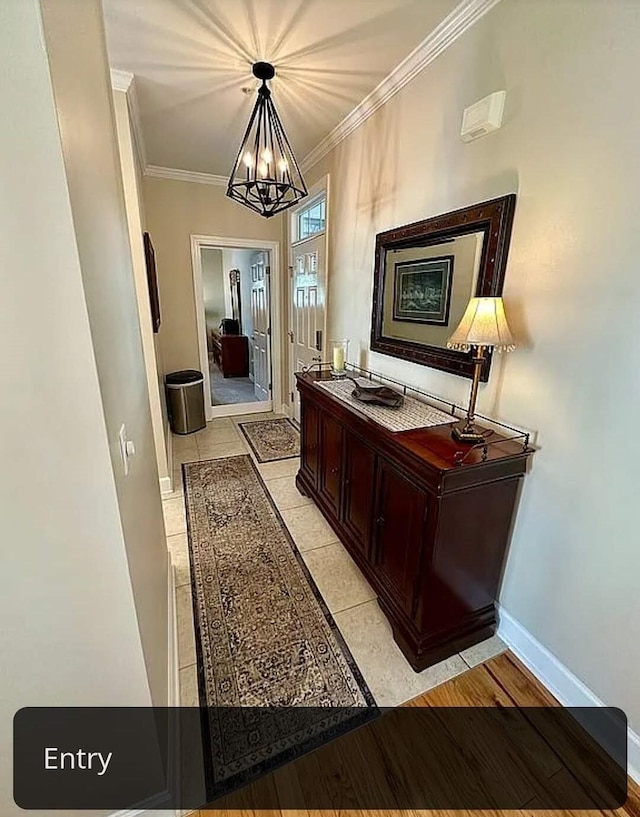 corridor featuring an inviting chandelier, crown molding, and light hardwood / wood-style flooring