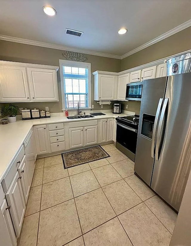 kitchen with appliances with stainless steel finishes, light tile patterned floors, white cabinetry, and sink