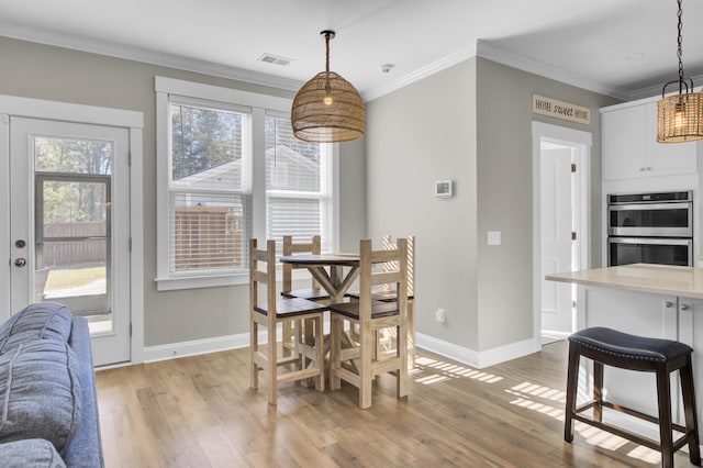 dining room with light wood-style flooring, baseboards, visible vents, and ornamental molding