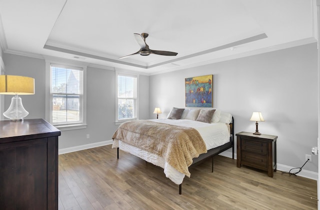 bedroom with baseboards, a tray ceiling, and wood finished floors