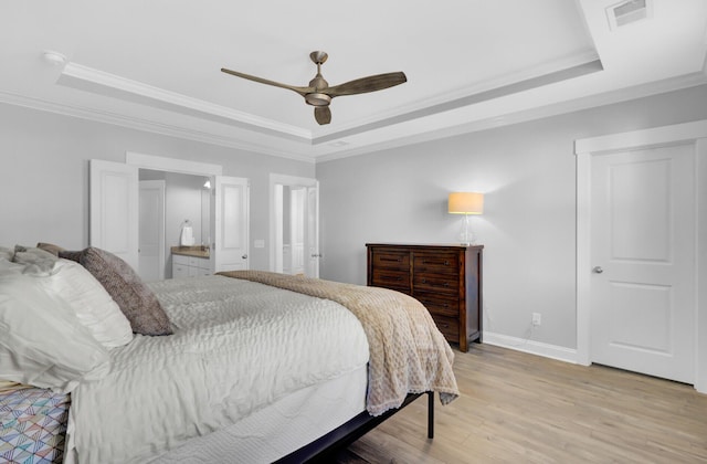 bedroom with visible vents, baseboards, a tray ceiling, crown molding, and light wood-type flooring