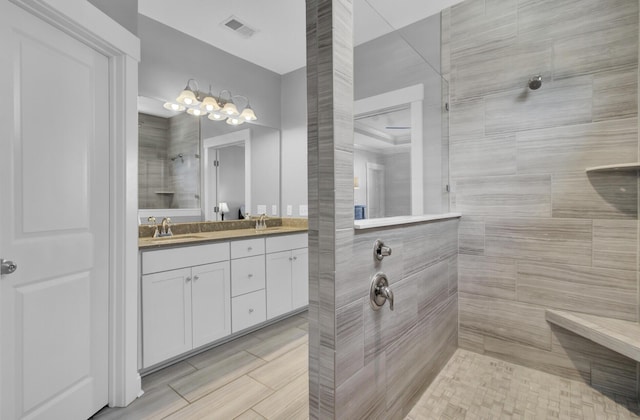 full bathroom with double vanity, a walk in shower, visible vents, and a sink