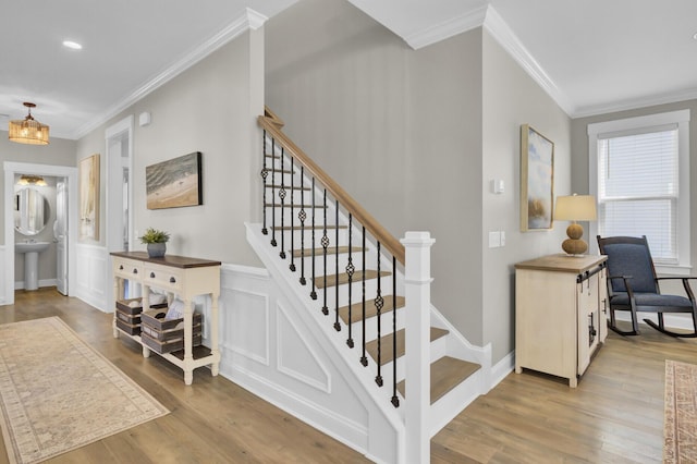 stairs featuring crown molding, a decorative wall, wood finished floors, and baseboards