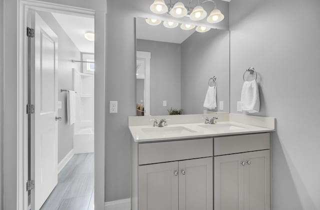 bathroom featuring a sink, baseboards, bathing tub / shower combination, and double vanity