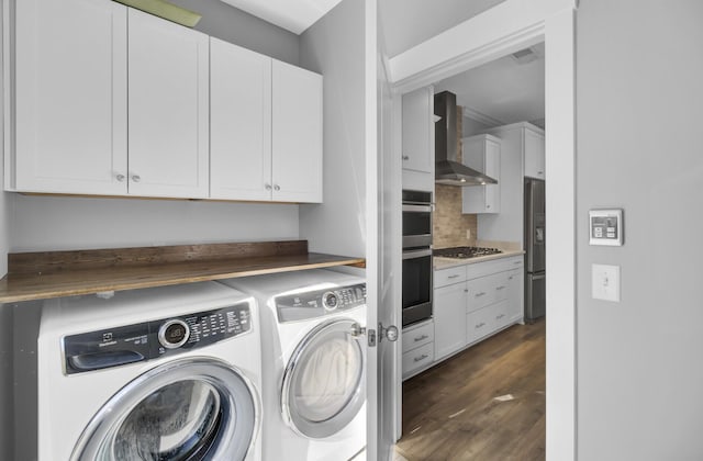 laundry area featuring washer and dryer, cabinet space, and dark wood-style flooring