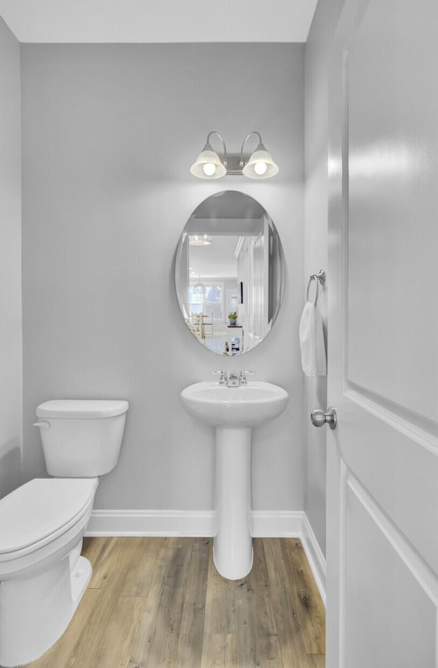 bathroom featuring toilet, wood finished floors, and baseboards