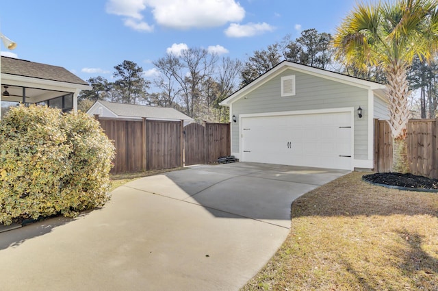 garage with concrete driveway and fence