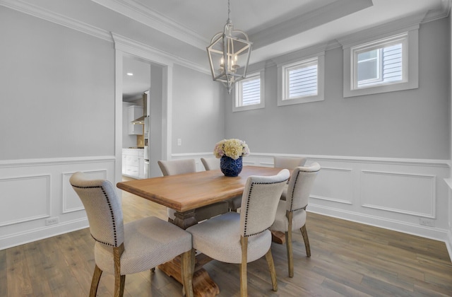 dining area featuring dark wood-style floors, a tray ceiling, ornamental molding, wainscoting, and a notable chandelier