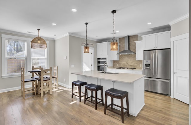 kitchen with a breakfast bar, ornamental molding, decorative backsplash, stainless steel appliances, and wall chimney exhaust hood