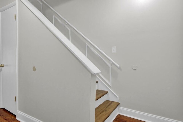 staircase featuring wood finished floors and baseboards