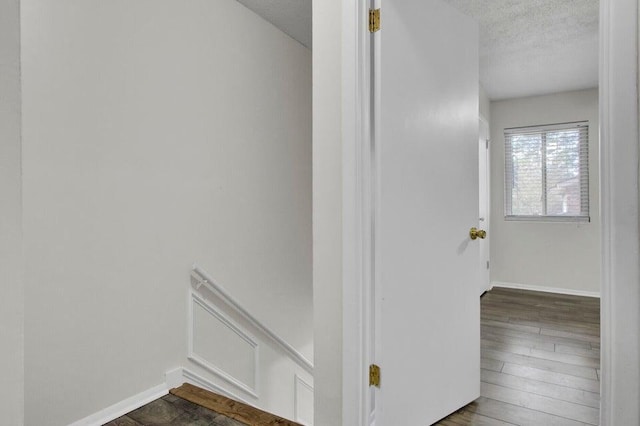 interior space with a textured ceiling, baseboards, and wood finished floors