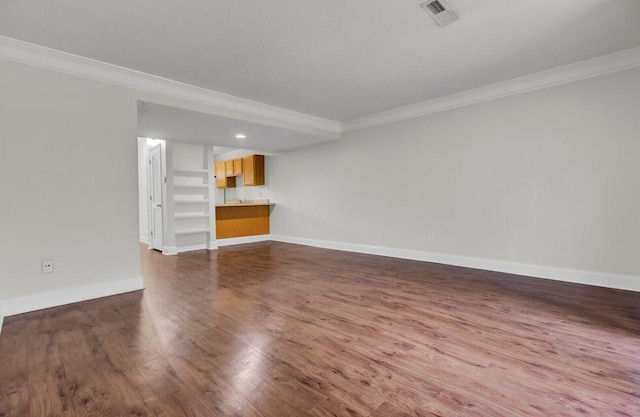 unfurnished living room with baseboards, wood finished floors, visible vents, and crown molding