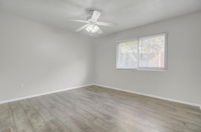 spare room featuring wood finished floors, a ceiling fan, and baseboards