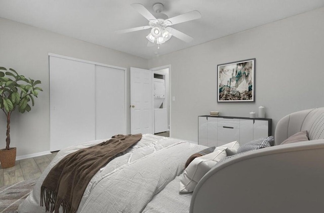 bedroom with ceiling fan, a closet, wood finished floors, and baseboards