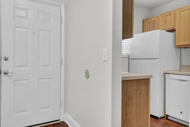 kitchen with light brown cabinets, white appliances, wood finished floors, baseboards, and light countertops