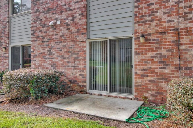 property entrance with brick siding and a patio