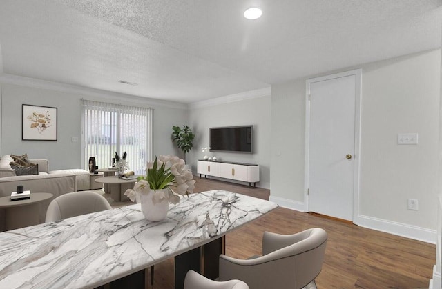 dining room with crown molding, a textured ceiling, baseboards, and wood finished floors