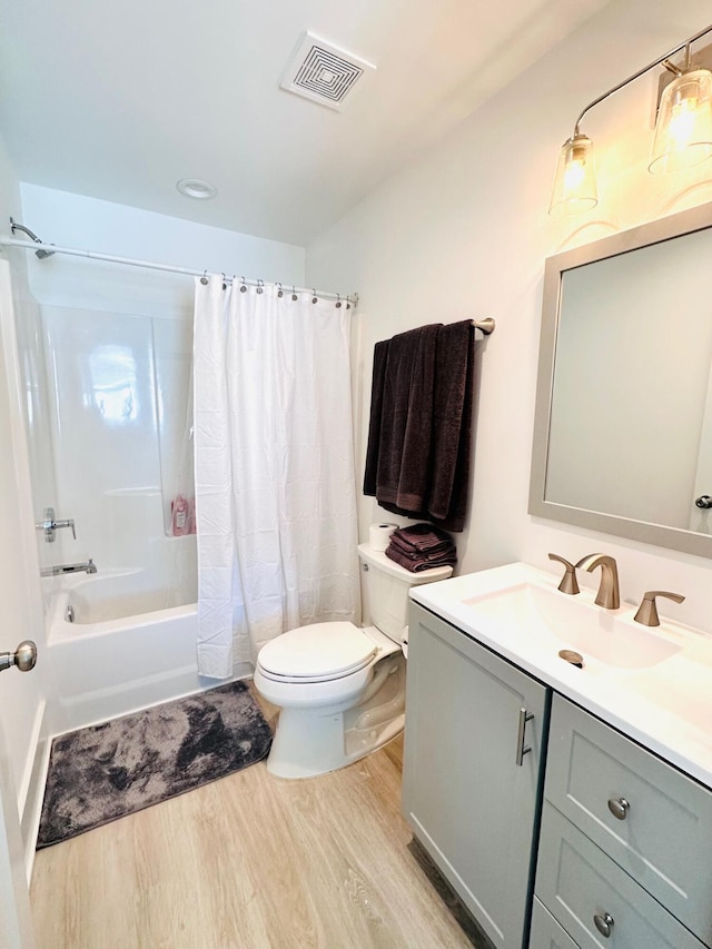 full bathroom with vanity, hardwood / wood-style floors, shower / tub combo, and toilet