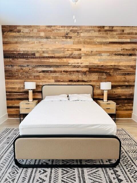 bedroom with wood-type flooring and wood walls