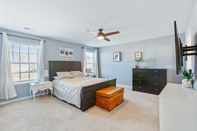 bedroom featuring a ceiling fan, light colored carpet, visible vents, and baseboards