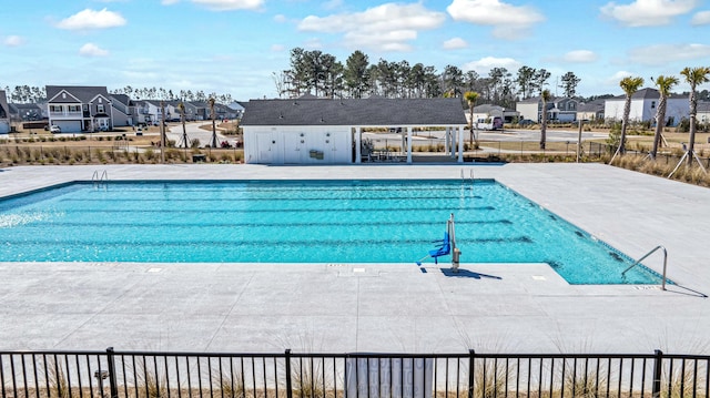 pool featuring a patio, fence, and a residential view