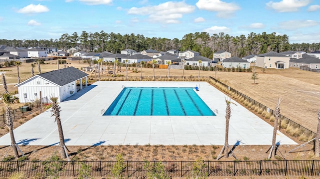 community pool featuring a patio area, a residential view, and fence