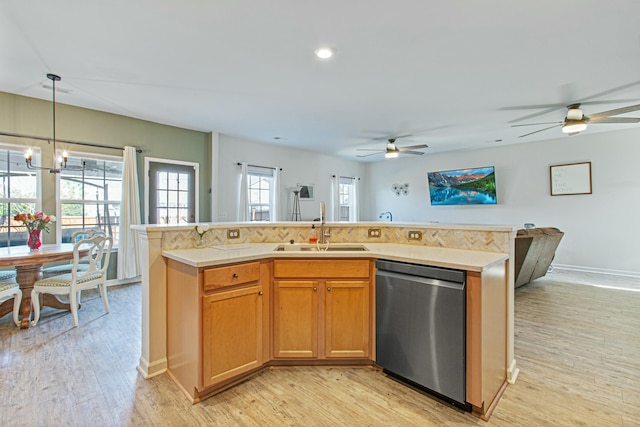 kitchen featuring dishwasher, an island with sink, light wood-style flooring, light countertops, and a sink