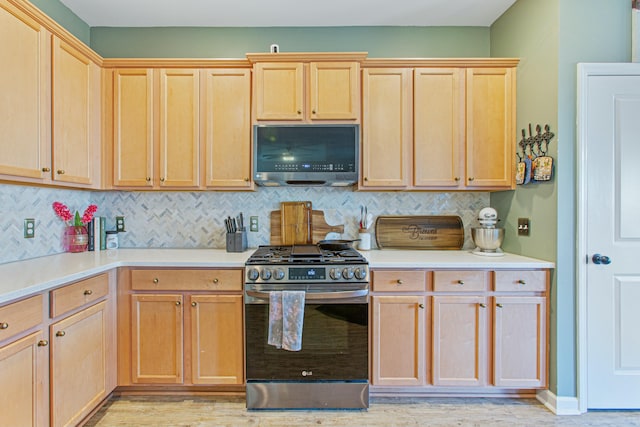 kitchen featuring light countertops, stainless steel gas range oven, backsplash, and light brown cabinets