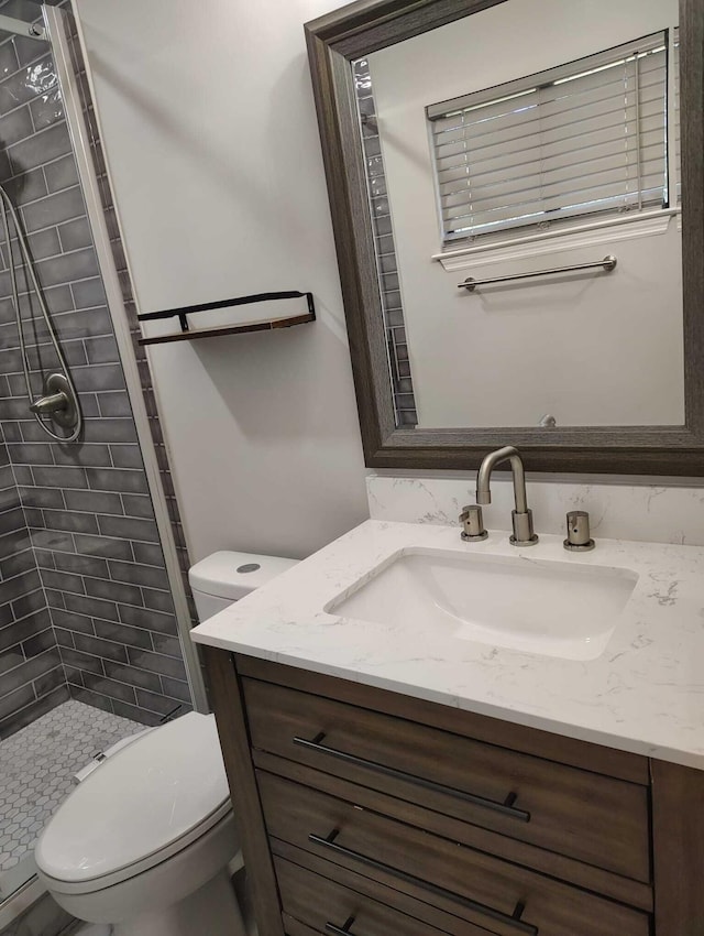 bathroom with a tile shower, vanity, and toilet