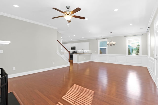 unfurnished living room with ceiling fan with notable chandelier, dark hardwood / wood-style flooring, crown molding, and sink