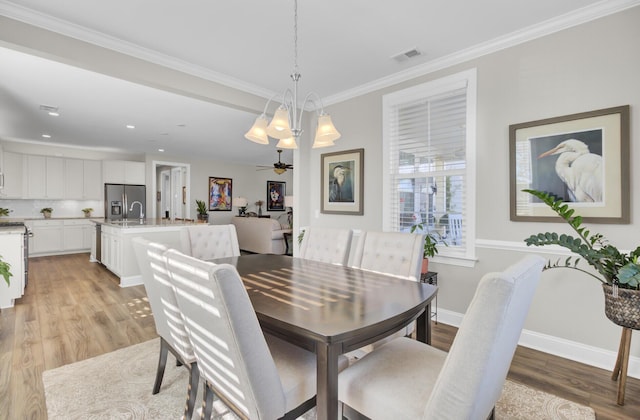 dining area featuring ornamental molding, sink, ceiling fan, and light wood-type flooring